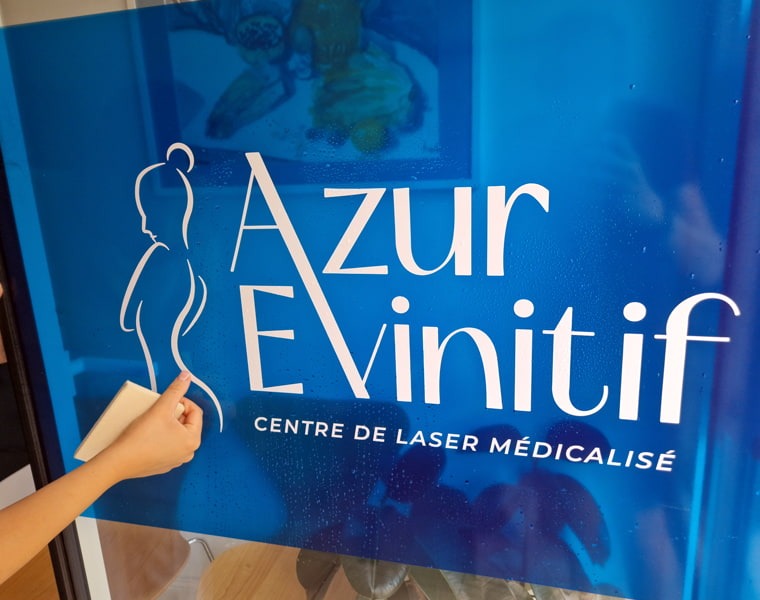 Adhésif vitrine Azur Evinitif Pose d’adhésif vitrine Azur Evinitif avec logo blanc sur fond bleu à Nice