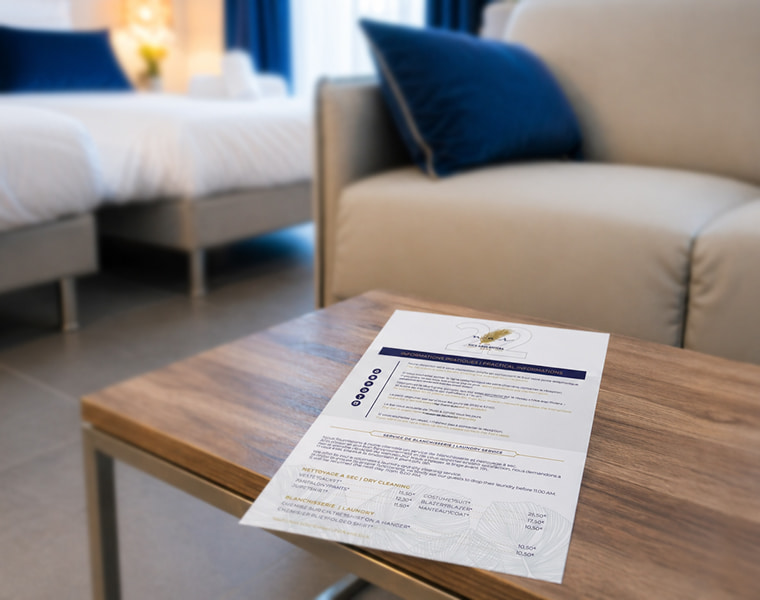 Document d’informations pratiques de chambre Hôtel Nice Azur Riviera posé sur table en suite hôtelière