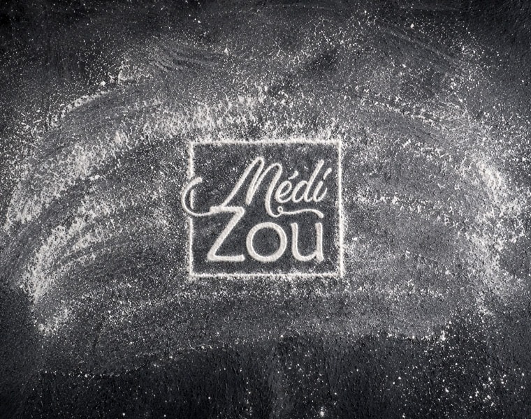 Identité visuelle MédiZou – Logo de pizzeria artisanale en Seine-et-Marne Logo MédiZou dessiné dans la farine sur fond noir pour une identité visuelle de pizzeria artisanale